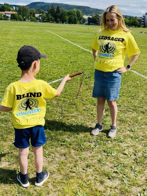 Liten gutt med ryggen til og dame som smiler til han.